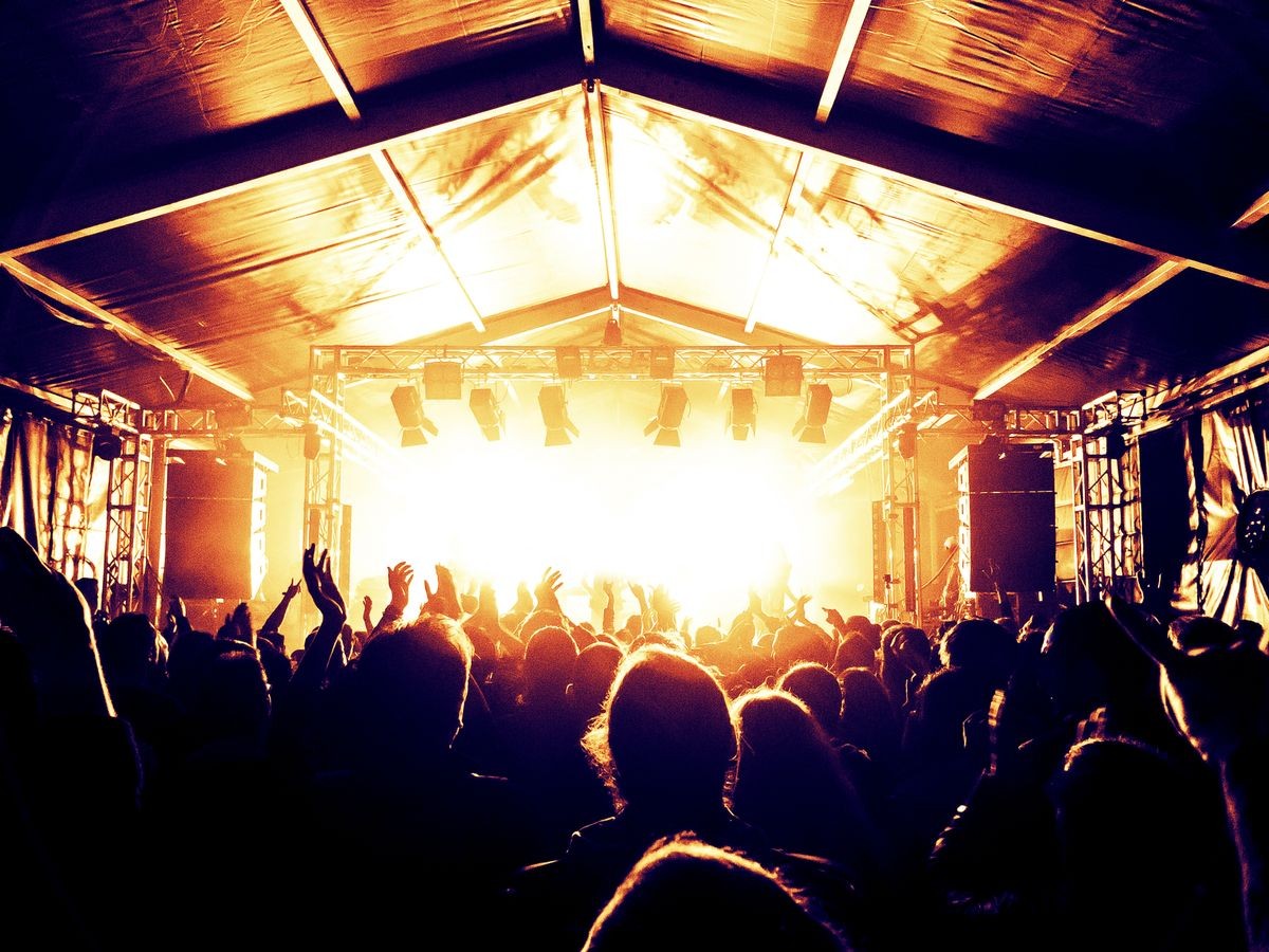 Golden stage in a concert venue, people silhouettes are visible in front of it